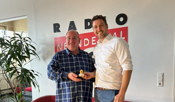 Radio Neandertal Moderator Daniela Patano und WILKA Geschäftsführer Robert Schlieper vor dem Radio Neandertal Logo