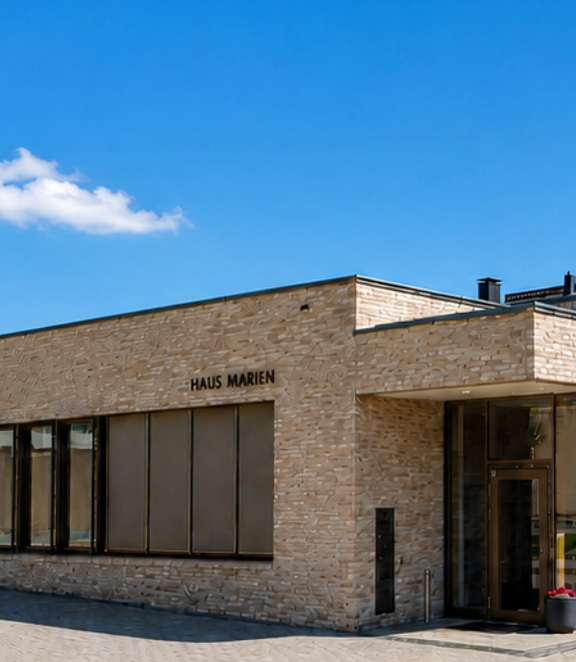 WILKA Referenzprojekt Haus Marien: modernes Kirchen- und Gemeindezentrum mit großzügiger Glasfassade, heller Natursteinarchitektur und barrierefreiem Eingangsbereich.
